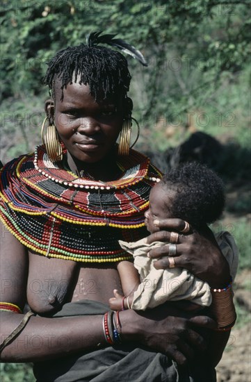 KENYA, People, Pokot tribeswoman wearing traditional bead jewellery holding baby.