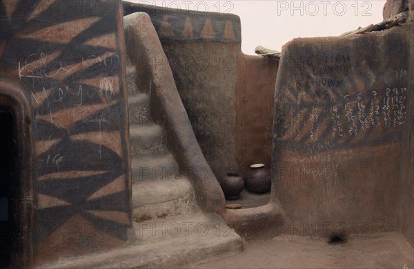 GHANA, North, Architecture, Traditional mud architecture.  Steps to flat roof where crops are dried and kitchen area.  Walls painted with broken calabash pattern in red and black.