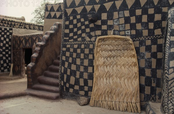 GHANA, North, Architecture, Traditional mud architecture.  Steps to flat roof where crops are dried and woven straw door.  Walls painted with black and natural chequered design.