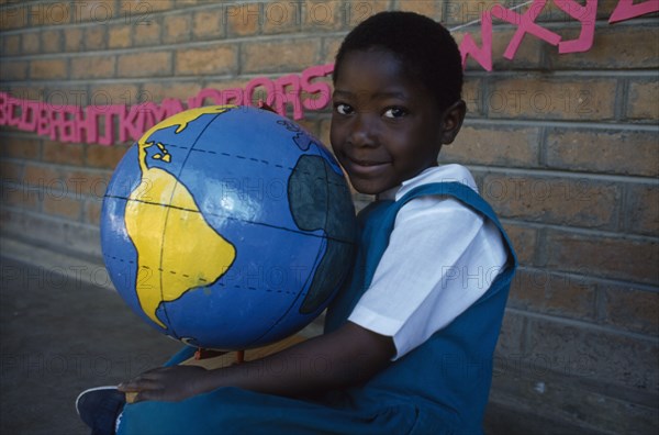 MALAWI, Blantyre, Portrait of child holding papier mache globe teaching aid made by PAMET from recycled materials.