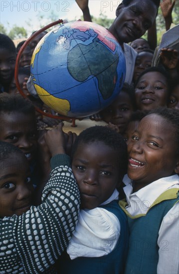 MALAWI, Blantyre, Children holding papier mache globe teaching aid made by PAMET from recycled materials.