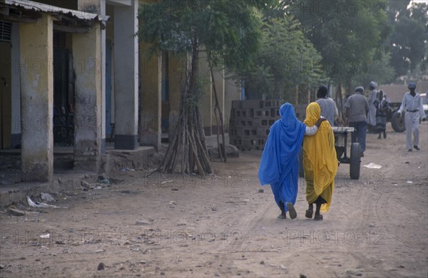 ERITREA, Tessanie, Two women with one woman resting her hand on others shoulder walking along road wearing colourful muslim clothing