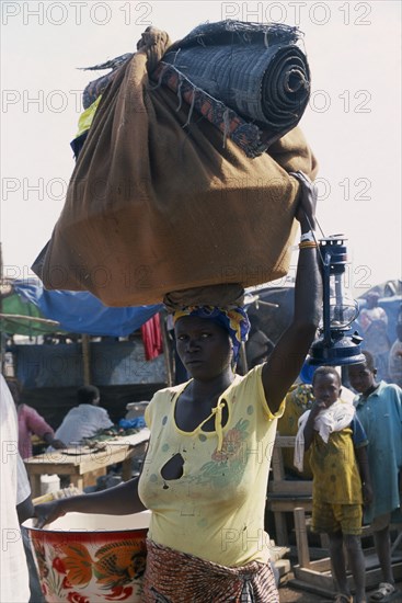 GUINEA, Kissidougou, Camp for Sierra Leonean Refugees. Woman carrying sack on her head arriving in camp.