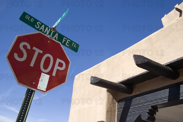 USA, New Mexico, Santa Fe, Stop sign on the Old Santa Fe Trail beside and adobe Pueblo Revival style building