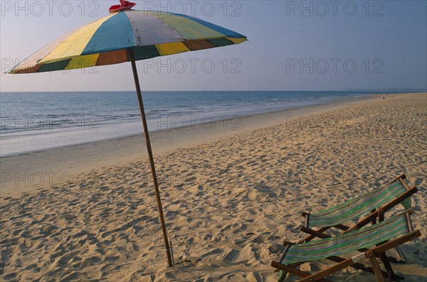 THAILAND, North Phuket, Takua Pa district, "Khao Lak, A multi coloured parasol and two deck chairs on the sandy beach."