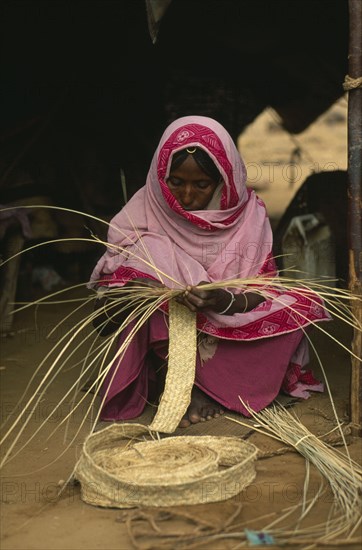 SUDAN, North East, Work, Eritrean woman in Gadum Gafriet refugee camp making birrish matting woven from palm leaves and used for tents and prayer mats