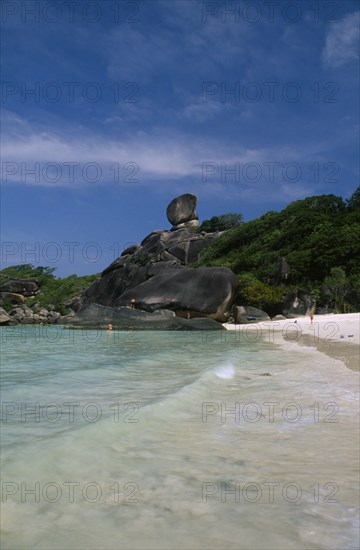 THAILAND, Koh Similan  , Sail Rock, View from the water’s edge of people on the sandy beach and climbing on the rocky coast line.