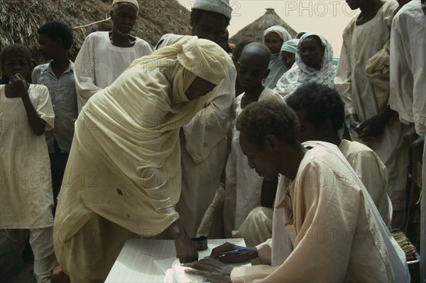 SUDAN, Kordofan Province, Umm Eshera, Signing for sorghum received in food distribution organised by CARE International with thumb print.