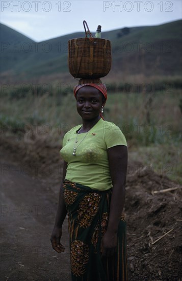 CAMEROON, People, Women, Portrait of young woman carrying woven basket on her head.