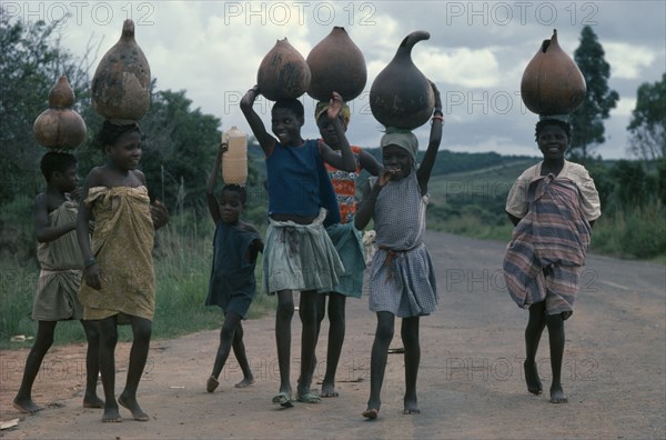 ANGOLA, People, Girls, Group of young girls returning from fetching water and carrying gourds on their heads.