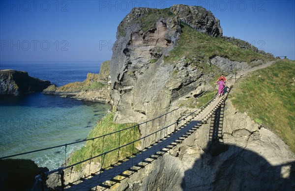 IRELAND, County Antrim, Carrickarede, Visitors crossing narrow rope bridge on the Irish coast.