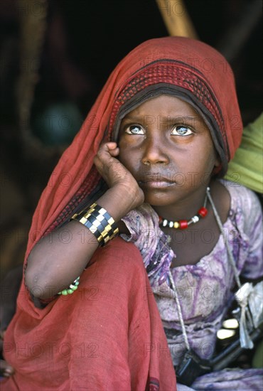 SUDAN, North East, Gadem Gafriet Camp, Portrait of Beni Amer Beja nomad refugee girl with chin resting on hand.