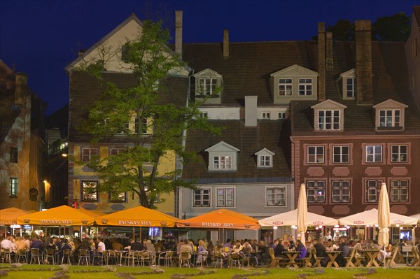 LATVIA, Old Riga, "Rows of floodlit bars, people sat at outside tables with large parasols."