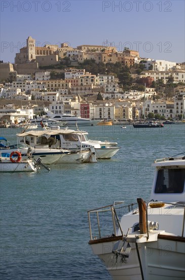 SPAIN, Balearic Islands, Ibiza, "View across the port, Eivissa. Various sized boats in water, buildings set on a hill behind."