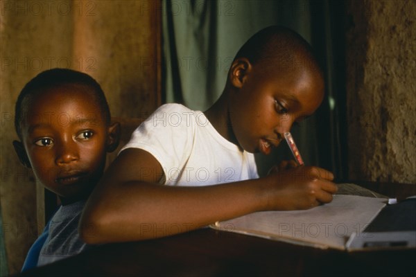 RWANDA, Akagera, "Children of Tutsi returnee family doing homework.  The family fled to Uganda over thirty years ago, but have returned under the new regime."