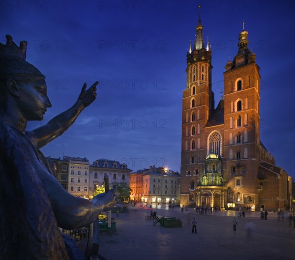 POLAND, Krakow, St Mary's Church in Rynek Glowny with part of the Adam Miekiewicz Memorial in the foreground.