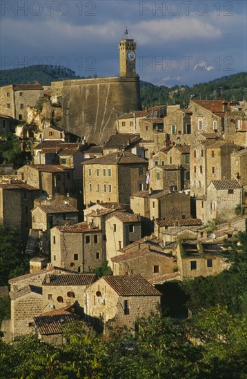 ITALY, Tuscany, Sorano, Etruscan town.  View over stone houses with tiled rooftops and clock tower behind.
