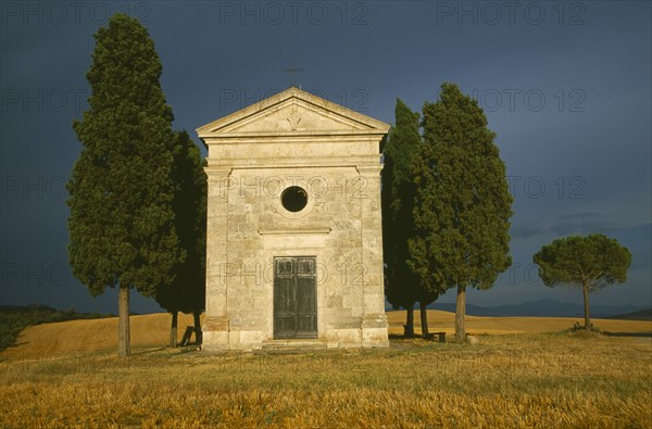 ITALY, Tuscany, Small stone chapel and cyrpress trees near San Quirico d’Orcia.