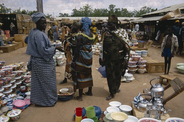 NIGER, Sahel, Niamey, Busy market scene with group of women looking at cooking utensils and pots in the foreground.