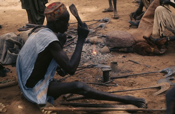 NIGER, Tahoua, Djerma metalsmith at market.