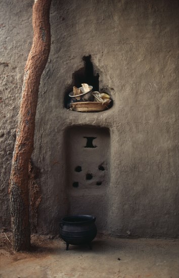 MALI, Housing, Detail of mud brick house near Kayes with bowl and basket in niche in wall and cooking pot on ground outside.