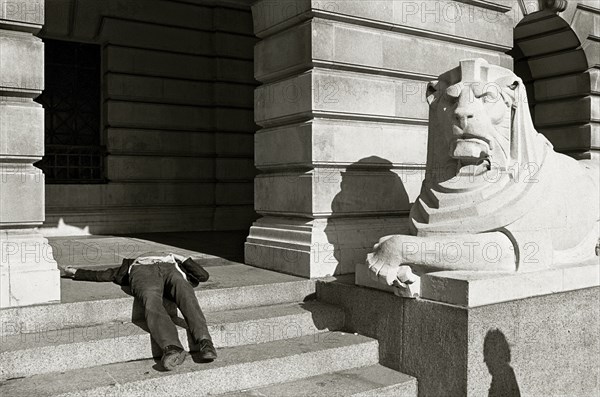 ENGLAND, Nottinghamshire, Nottingham, A drunk sleeps on the steps next to a lion statue outside the City Hall in Market Square