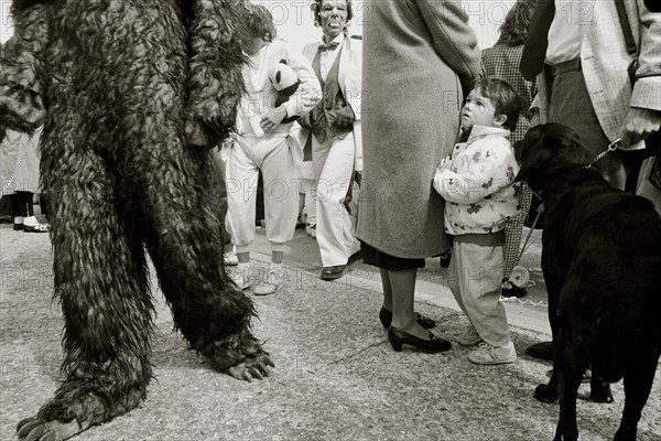 FRANCE, Bouches du Rhone, Arles, "A child watches as the crowd passes wearing fancy dress during a festival, black dog on a lead."