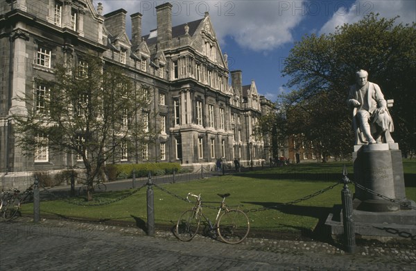 IRELAND, Dublin, Trinity College.  Exterior facade and grounds with chained bicycle and statue of mathmatician and theologian George Salmon provost of the college 1888-1904.