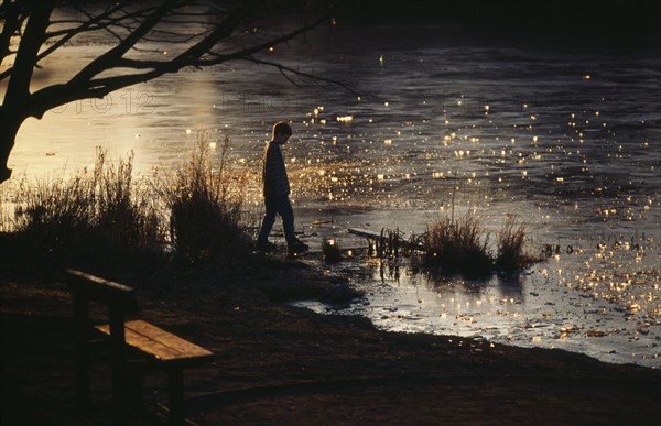 N. IRELAND, Landscape, Boy standing on shore of frozen lake testing ice with his foot.