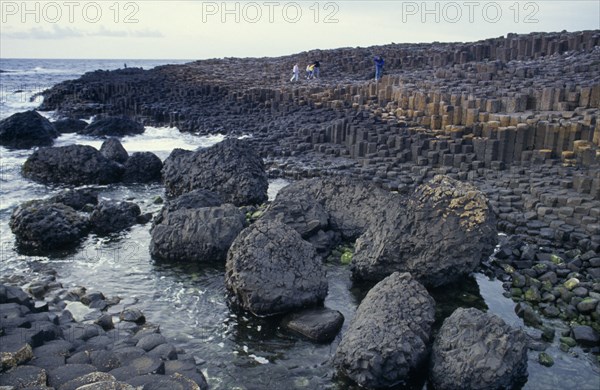 NORTHERN IRELAND, County Antrim, Giant’s Causeway, Visitors on rocky promontory of North West Moyle coast consisting of thousands of polygonal colimns of basalt attributed to rapidly cooling lava.