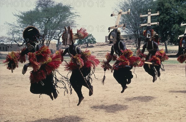 MALI, Ceremony, Dogon masked dancers leaping in line.