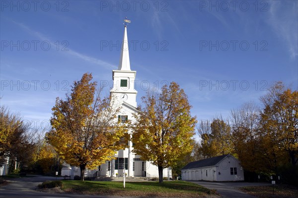 USA, New Hampshire, Dublin, "White church with clock on spire and tall columns at entrance,  golden leaves on trees."
