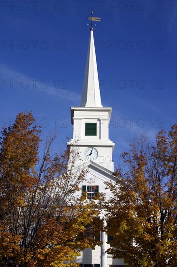 USA, New Hampshire, Dublin, "Close up of white church with clock on spire and tall columns at entrance,  golden leaves on trees."