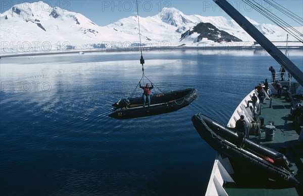 ANTARCTICA, Ships, Lowering Zodiacs for taking passengers ashore. Person standing in the small boat whilst being lowered.