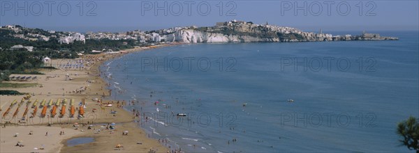 ITALY, Puglia, Peschici, "Promontorio del Gargano, The seaside Town resort by the Adriatic Sea. View along the beach to Town of Viesta"