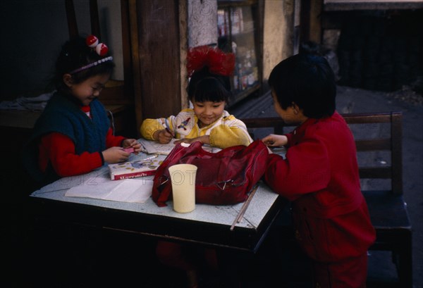 CHINA, Guiyang, Children doing homework outside house.