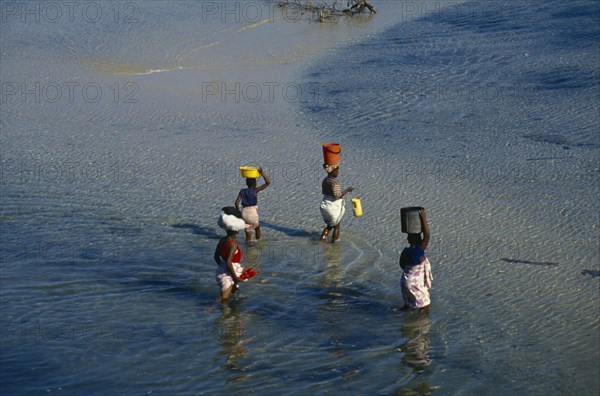 MOZAMBIQUE, Pemba, Elevated view over women wading in the sea carrying bowls and buckets on their heads.