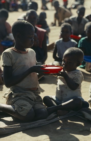 MOZAMBIQUE, Zambezia Province, Mugulama, Children sharing bowl at feeding centre for displaced people run by World Vision Aid charity.