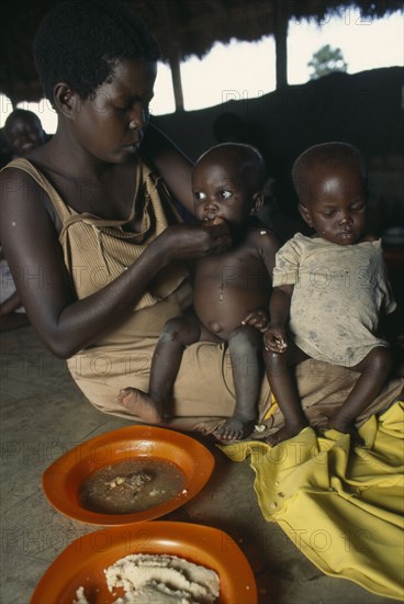 UGANDA, West Nile, Sudanese refugee mother and children at feeding centre for vulnerable people.