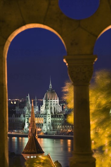 HUNGARY, Budapest, "Night time view of Parliament over the Danube from Fishermen's Bastion, viewed through arches."