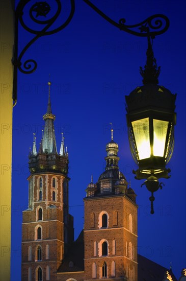 POLAND, Krakow, "Detail of St Mary's Church in Rynek Glowny, Night time with lit lamp with decorative bracket on wall."