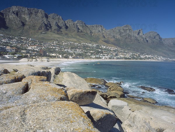 SOUTH AFRICA, Western Cape, Cape Penninsula, View across rocks towards Clifton bay and beach.  Hillside buildings with the Twelve Apostles behind