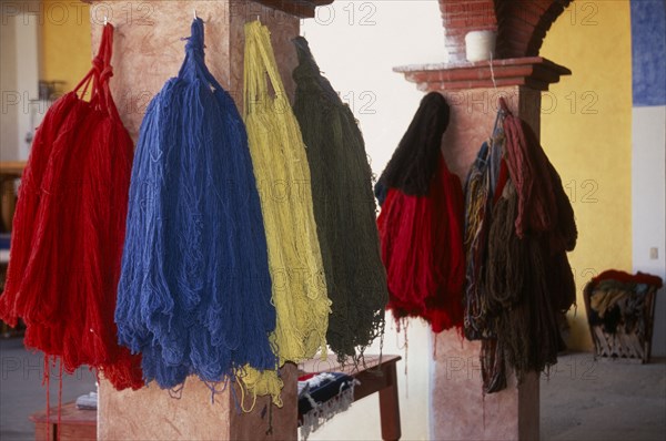 MEXICO, Oaxaca, Teotitlan del Valle. Different coloured thread handing on pillars in the weaving centre.