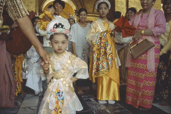 MYANMAR, Mandalay, Group all dressed up for ordination ceremony Mahamuni Paya. Young girl in foreground. Great sage Pagoda.