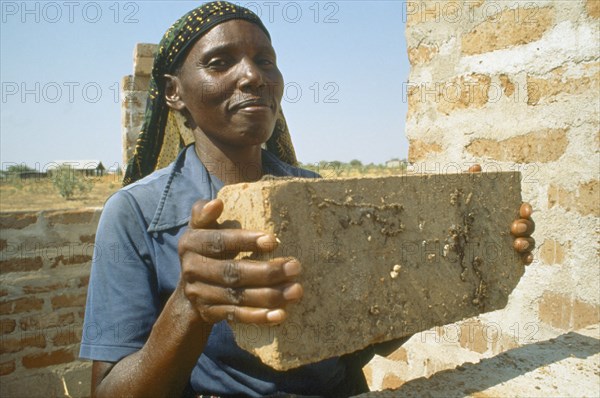 TANZANIA, Shinyanga, Woman in Mshikimano squatter settlement taught to make bricks for building her house.