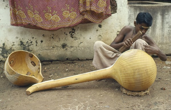 INDIA, Tamil Nadu, Tanjore, "Instrument maker finishing a veena, a traditional stringed instrument consisting of a hollow wooden body and long neck. "