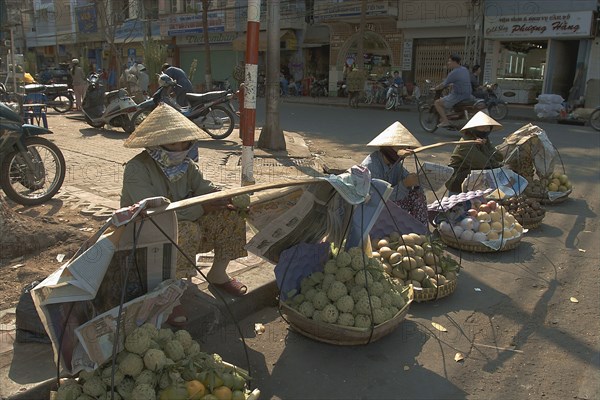 VIETNAM, South, Ho Chi Minh City, Fruit sellers wearing conical hats on the street in the centre of town