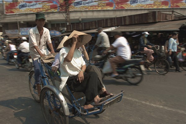 VIETNAM, South, Ho Chi Minh City, Two women riding a Cyclo on a busy street