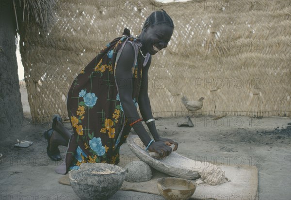 SUDAN, People, Shilluk woman grinding sorghum to make bread.