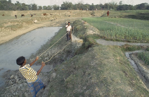 BANGLADESH, Dinajpur, Men operating irrigation system incorporating manual swing basket.